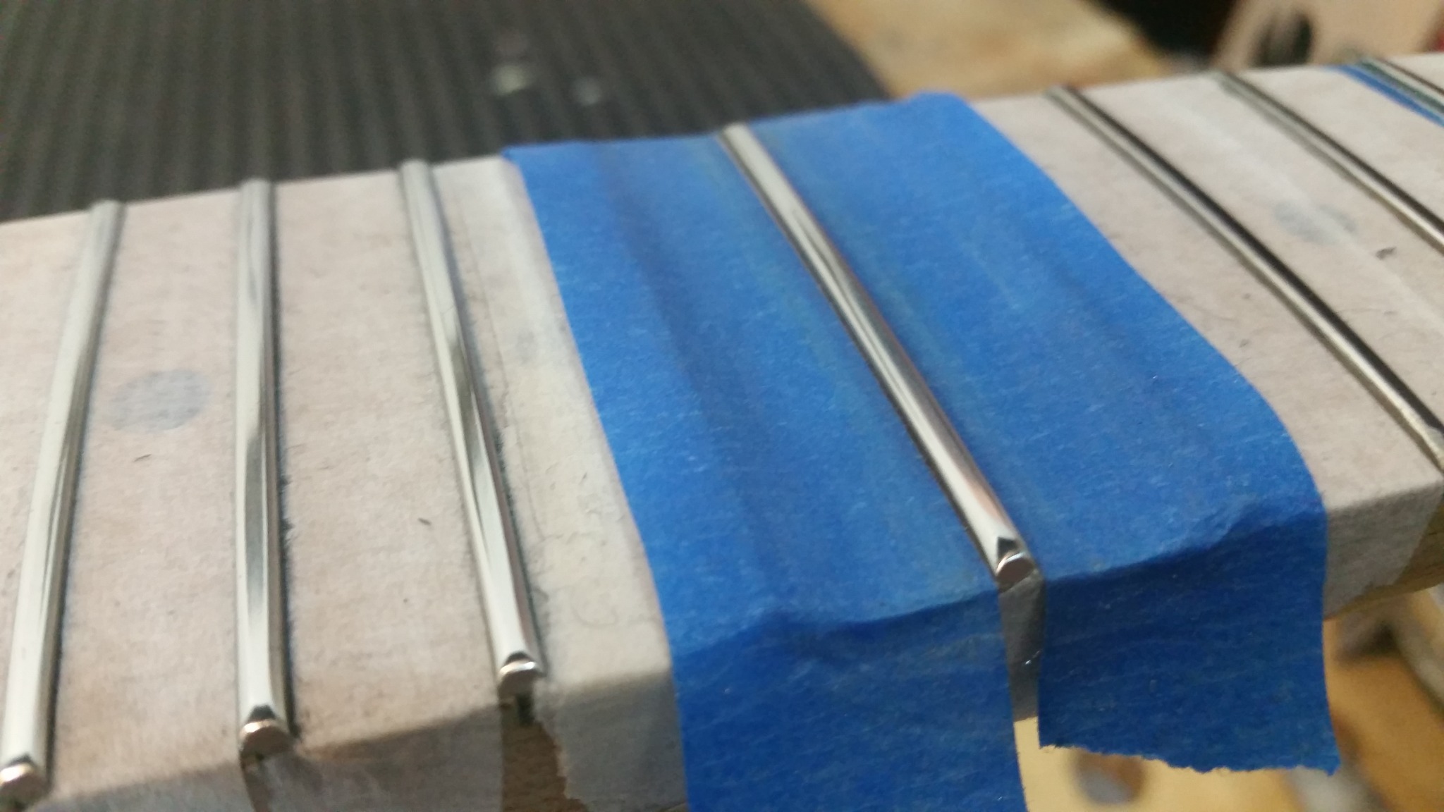 Hastes metálicas apoiadas sobre uma superfície de madeira com fita azul.